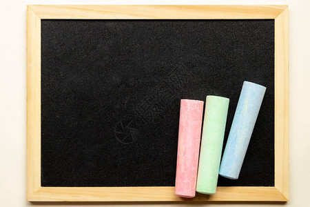 用三支彩色蜡笔的空黑板黑色板上的粉红色蓝色和绿色粉笔有文本的地方图片