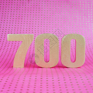 在明亮粉红圆点背景的700号金体积图片