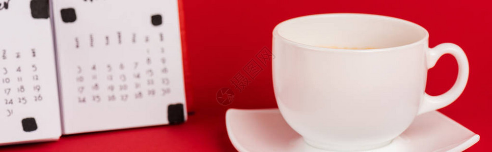 红色背景上一杯咖啡和日历的全景照片图片