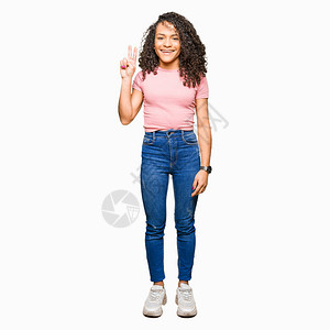 穿着粉红色T恤的卷发年轻美女用手指举起第二指头微笑着自信和快乐地笑着图片