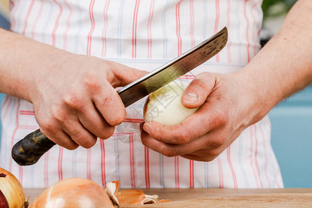 男厨师在特写中剥洋葱和刀子有图片