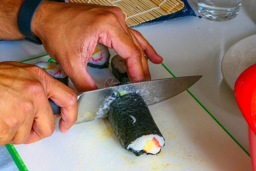 在厨房里在家做寿司卷然后切图片