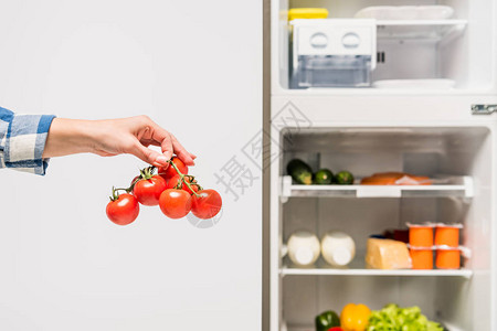 妇女将西红柿放在露天冰箱附近的露天冰箱旁图片