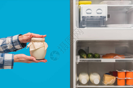 女在露天冰箱和冷冻柜附近含酸奶油的妇女的作物风景图片