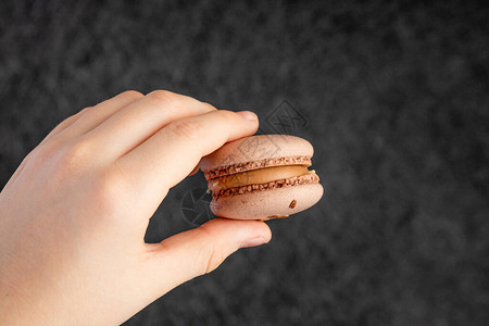 巧克力马卡龙装满奶油在黑暗背景的手图片