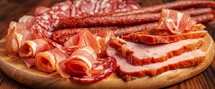 木制砧板上的各种肉类小吃香肠火腿培根熏肉制品库存图片