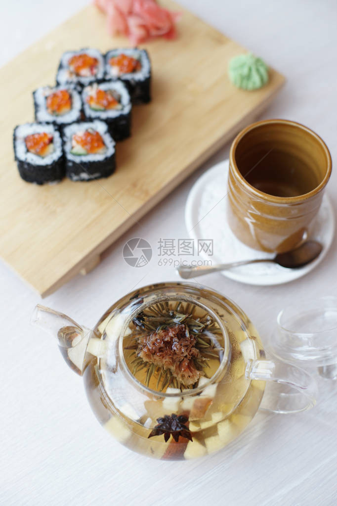 桌子背景上配有寿司卷和水壶茶的日本料理图片