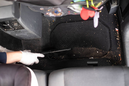 使用真空吸尘器清洁汽车的女手顶视图图片