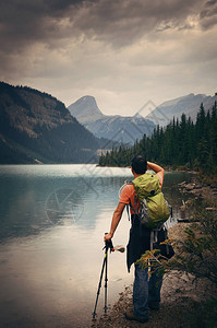 徒步旅行者在有山林和云的雨天在湖边休息图片