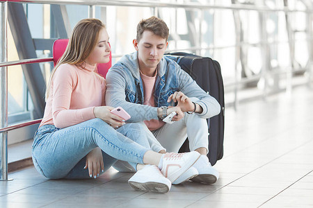 不幸的夫妇在机场等待他们延误的航班年轻人错过了他们的火车机场里图片