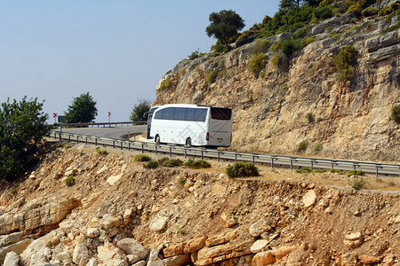一辆白色巴士沿着地中海沿途的山路行驶图片