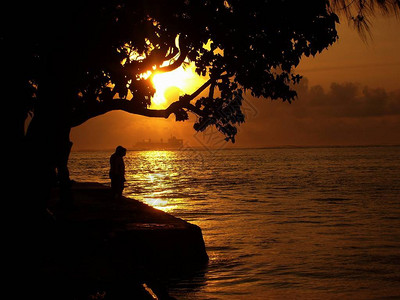 美丽的金色日落在赛潘环礁湖的水面上闪耀着光荣的反射与人们的轮廓和远方图片