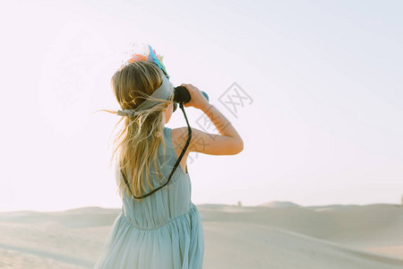小女孩在沙漠里看着望远镜图片