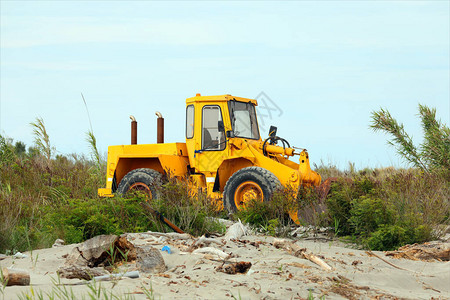 海滨的黄色大推土机在游客抵达前将沙子移图片