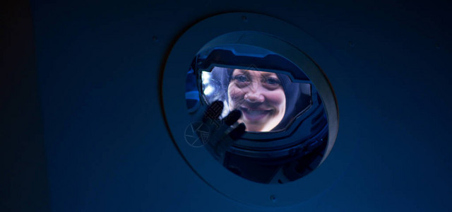 放大对一名女宇航员从太空飞船上挥舞相机图片
