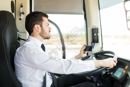 西班牙裔公共汽车司机用GPS导航器驾驶移动电图片