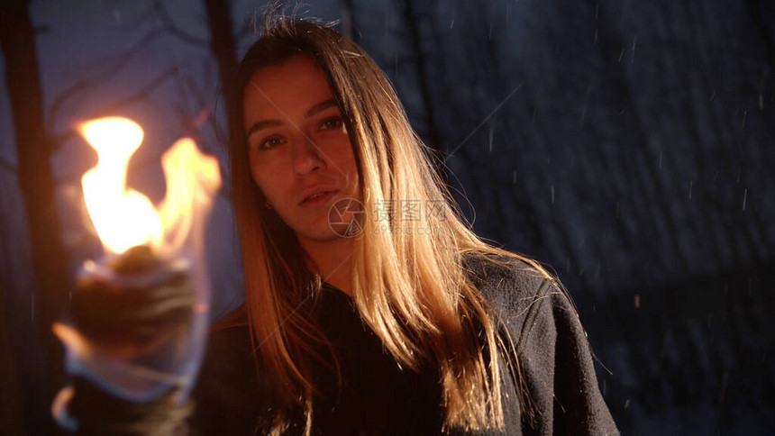 带着火炬的年轻女子站在冬天的森林里在雪瀑下看一些图片