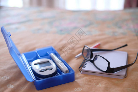 糖尿病测量工具和床上的眼镜图片