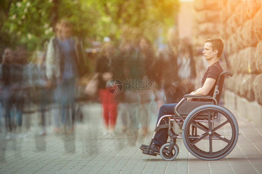 残疾人坐在人行道上人群流中轮图片