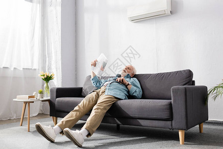 在家用空调在沙发上持报纸的背景图片