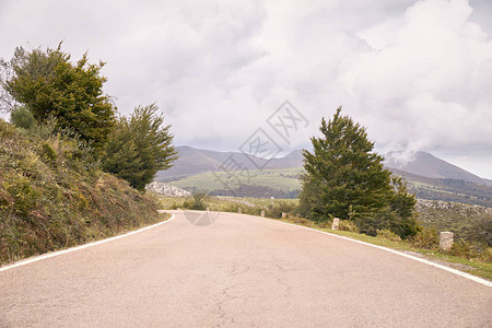 绿色田地与秋云下之间的风山道路前往最美的公路之旅图片