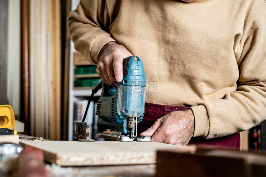 木匠的手与电动拼图特写在木工车间工作一名男子用电动拼图切割胶合板木图片