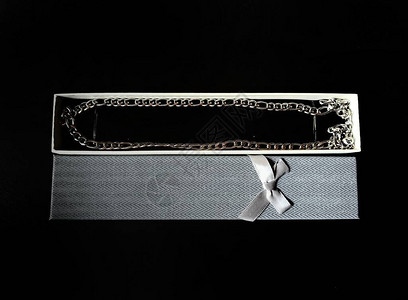 黑色背景中礼品盒中的银链图片