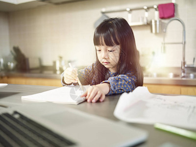 小亚洲女孩坐在厨房柜台在家图片