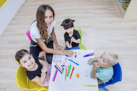 幼儿老师和学生的顶端景色在镜头前微笑同图片