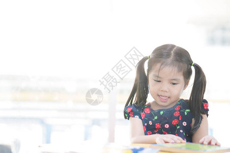 亚洲儿童可爱或小女孩快乐微笑或学生喜欢阅读故事书或丰富多彩的故事图片