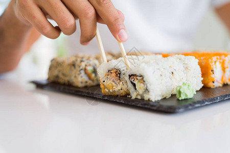 彩色寿司亚洲食品特写男人用筷子夹寿司片图片