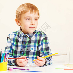 快乐的小男孩用彩色铅笔绘画图片