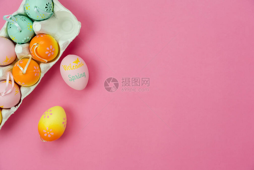 布置装饰快乐复活节假期背景概念的顶视图在办公桌上现代美丽的粉红色纸上平躺着五颜六色的兔子蛋和配饰设图片