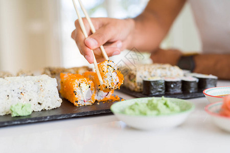 彩色寿司亚洲食品特写男人用筷子夹寿司片图片
