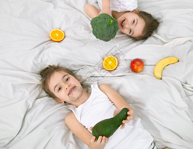 有两个可爱的小孩在轻薄的背景下玩水果和蔬菜图片