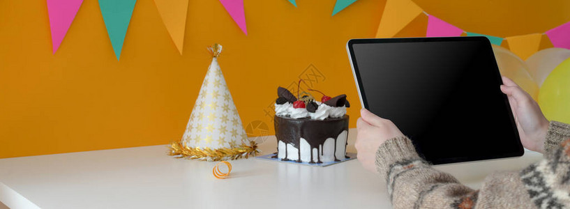 女在用蛋糕和派对帽坐在桌边时拿着数字片图片