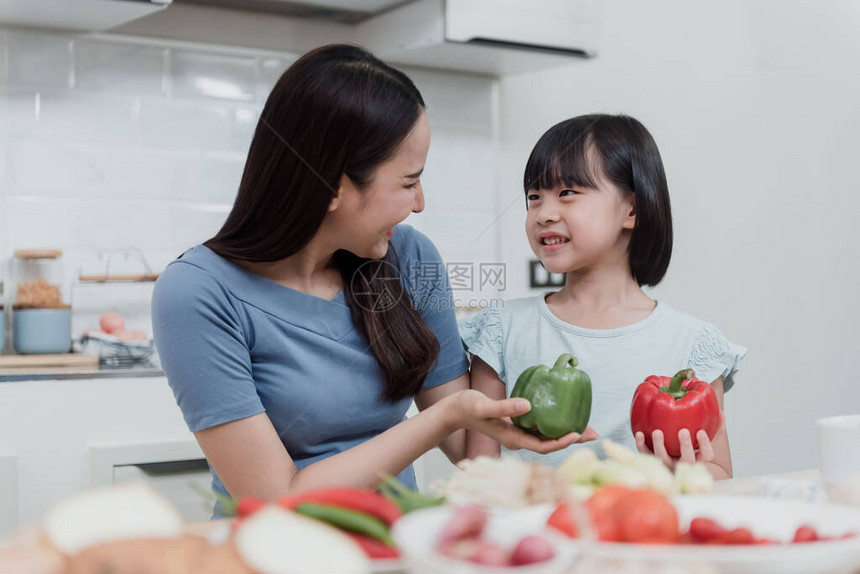美丽的女人和两个可爱的亚洲女孩正在家里的厨房里教烹饪两个人很开心这是一种新的图片