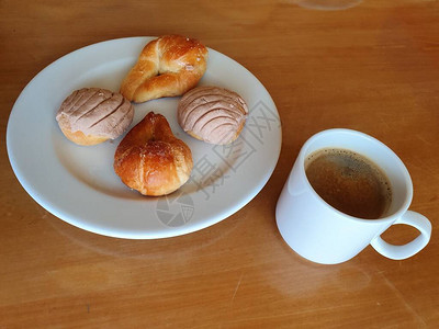 一杯咖啡木桌上放着甜面包片的盘子图片