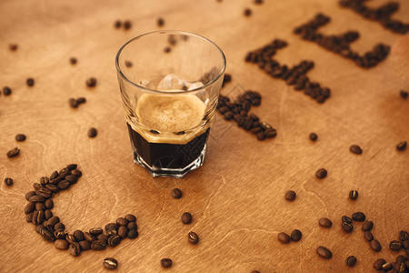 咖啡字由芳香烤咖啡豆和木桌上的热浓咖啡玻璃杯制成图片