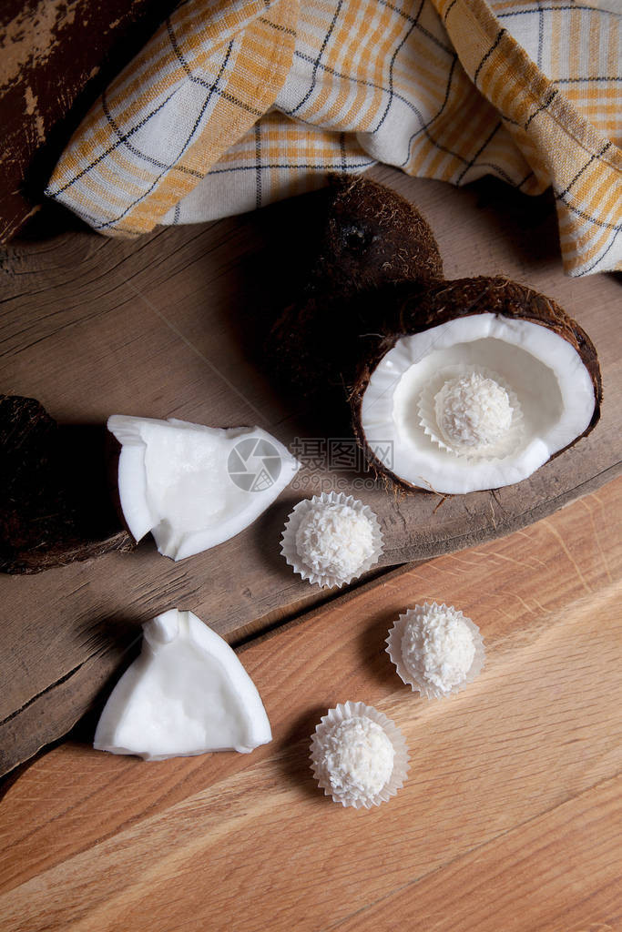 椰子和甜巧克力椰子松露椰子壳椰子片小块碎坚果和木制背景上的白巧克力椰子糖带壳的图片
