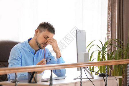 疲惫的商人坐在办公室的桌子旁图片