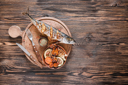 木制背景上准备好的鲭鱼和蔬菜的木板图片