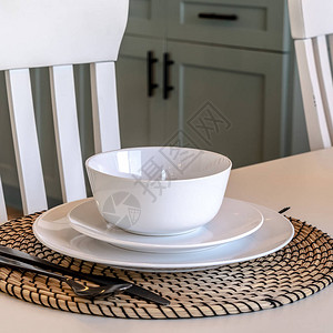 家的方形餐桌设置对椅子木地板和厨柜汤碗碟子盘子器皿和叉子都布置图片