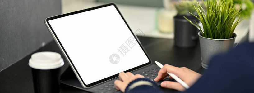 黑桌上配有咖啡杯和装饰的模拟数字平板电脑上打字的女自由职业妇图片