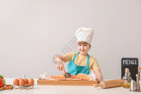 可爱的小厨师在浅色背景下烹饪图片