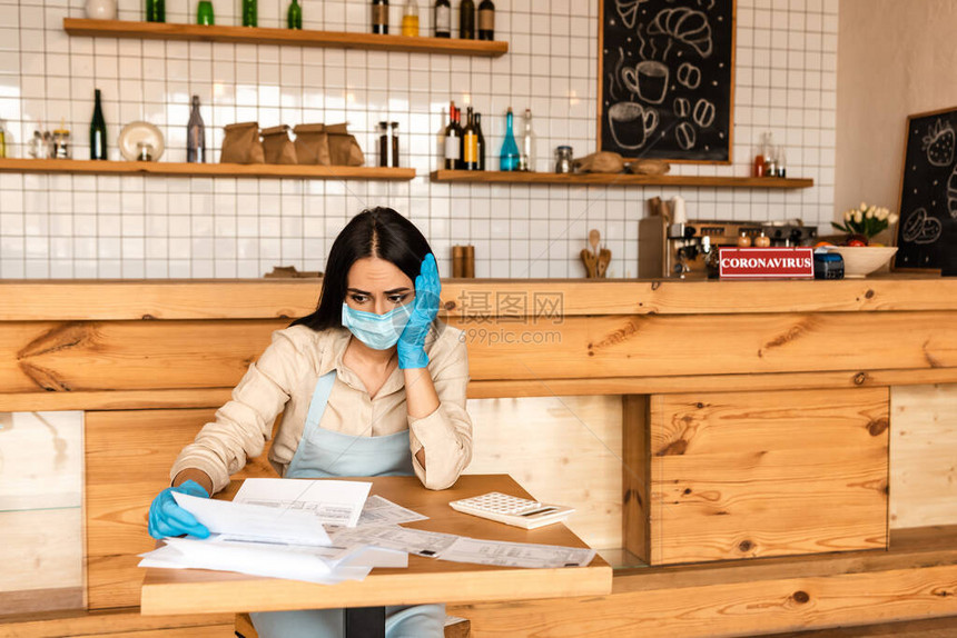 咖啡馆店主穿着医疗面具在桌子上的计算器图片