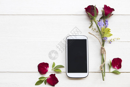 红玫瑰的移动电话在背景白木上图片