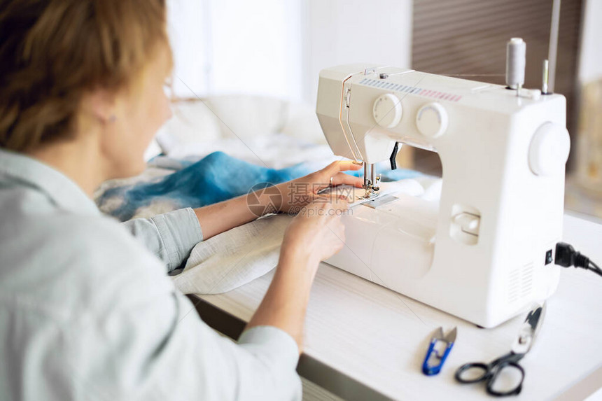 在裁缝讲习班上用布料在桌边的缝纫机缝制工艺作为一项小商业概图片