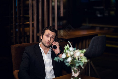 英俊的男人正在打电话坐在酒吧桌旁图片