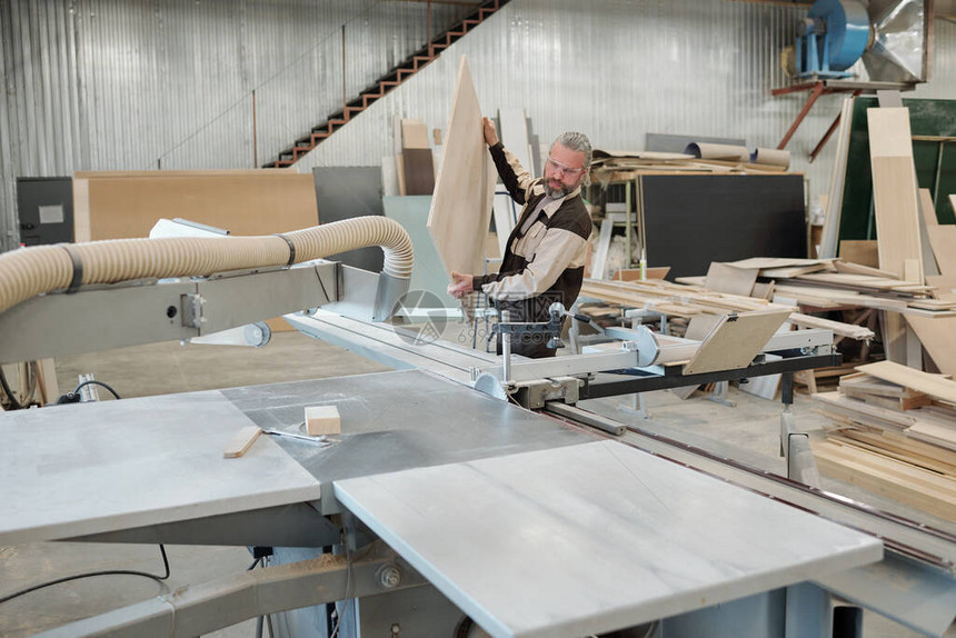 家具生产厂的高级工人在加工前将大型重木板放图片